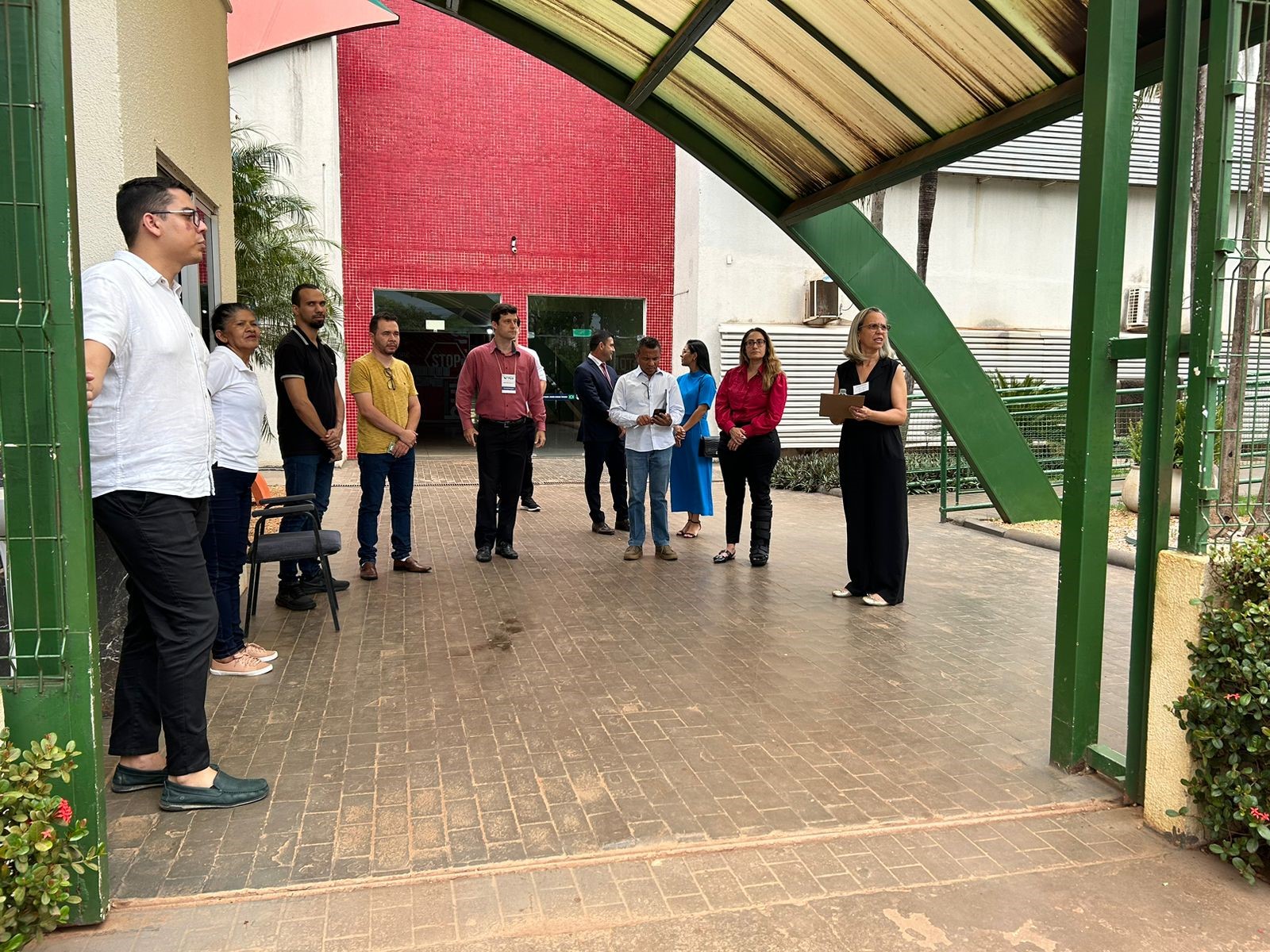 Grupo de nove pessoas em pé e vestidas formalmente de frente a Escola de Tempo Integral Padre Josimo.