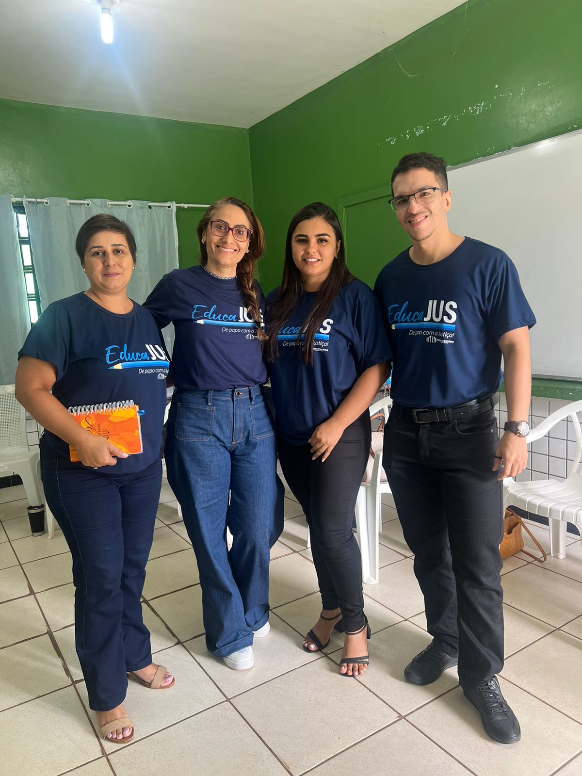 três mulheres e um homem trajados com uma blusa azul escuro com a palavra 'EducaJus' estampada com calças e calçados variados