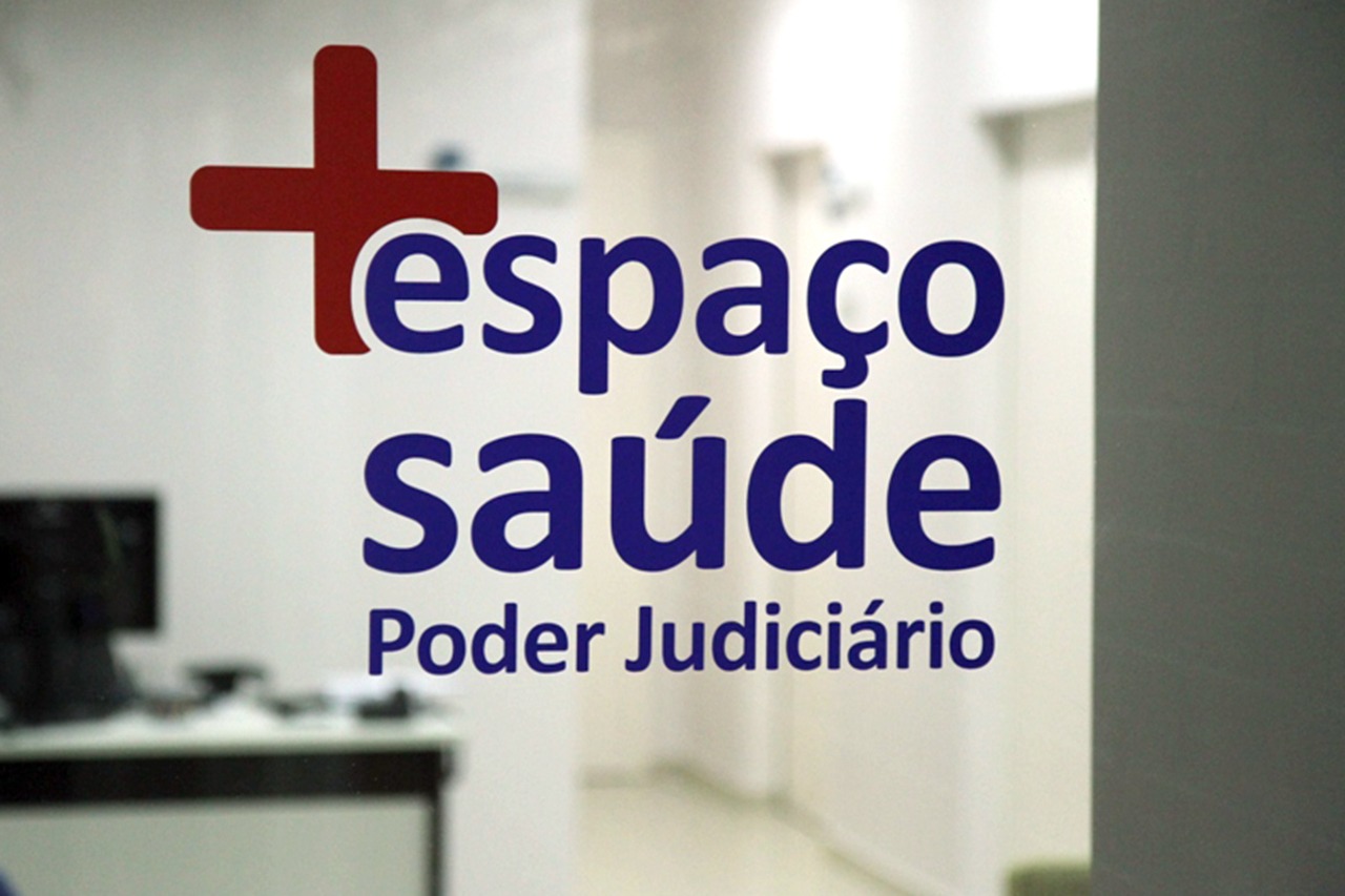 Imagem de parte da porta da entrada do Espaço Saúde com os dizeres "Espaço Saúde Poder Judiciário"