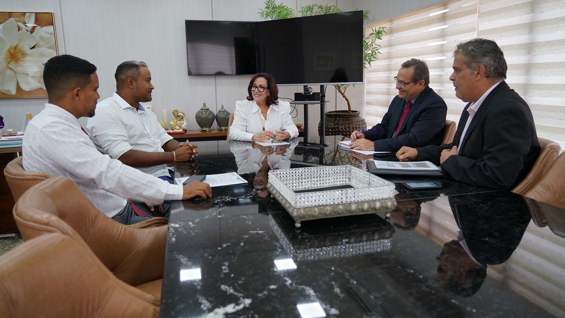 Imagem com cinco pessoas sentadas à mesa, entre elas, a presidente do TJTO e o prefeito de Brejinho de Nazaré