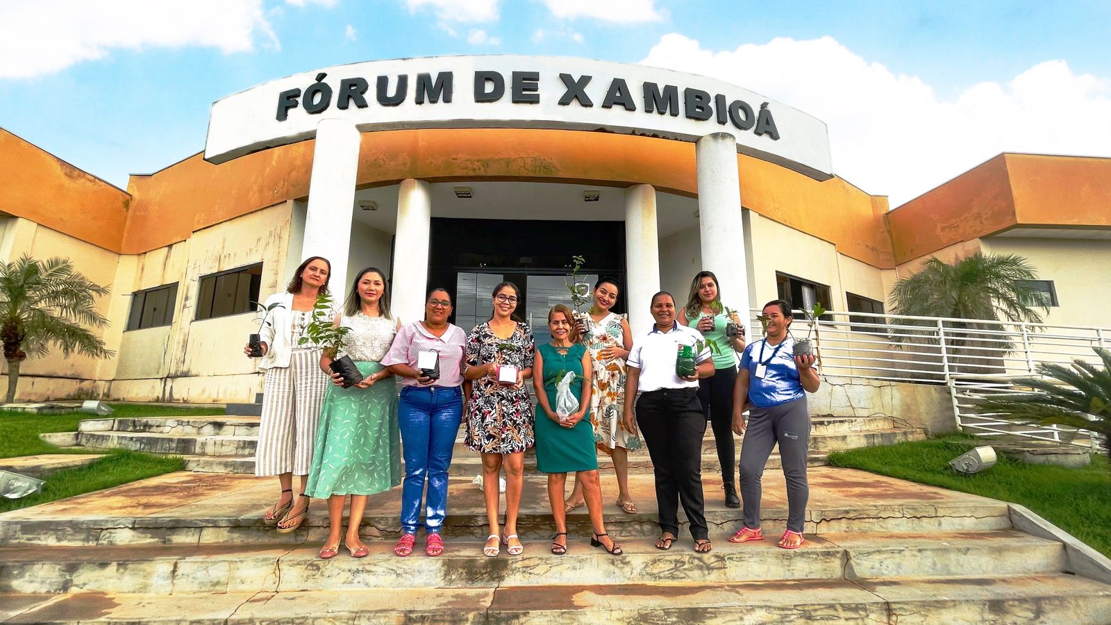 Mulheres seguram uma muda de planta em frente ao Fórum de Xambioá