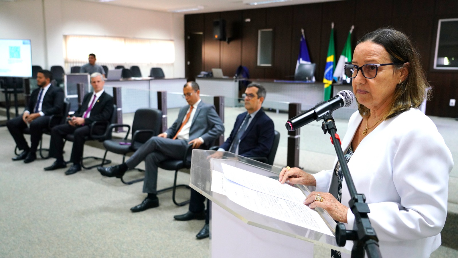 Desembargadora Maysa Vendramini falando para público presente na correição, em palanque, ao lado de autoridades presentes que estão sentados próximos