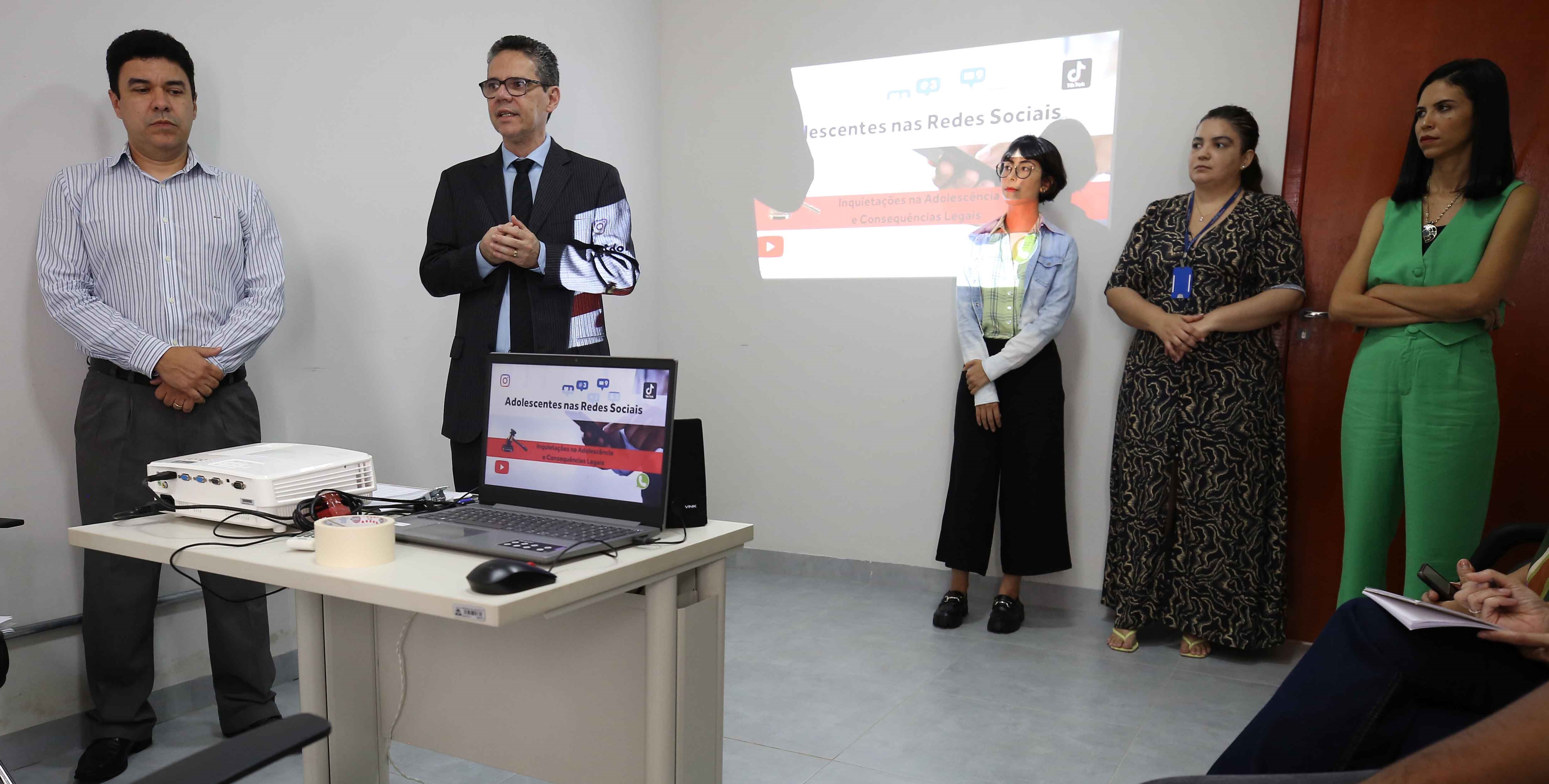 Imagem mostra quatro pessoas em pé durante uma palestra sobre uso das redes sociais no Núcleo de Atendimento Integrado