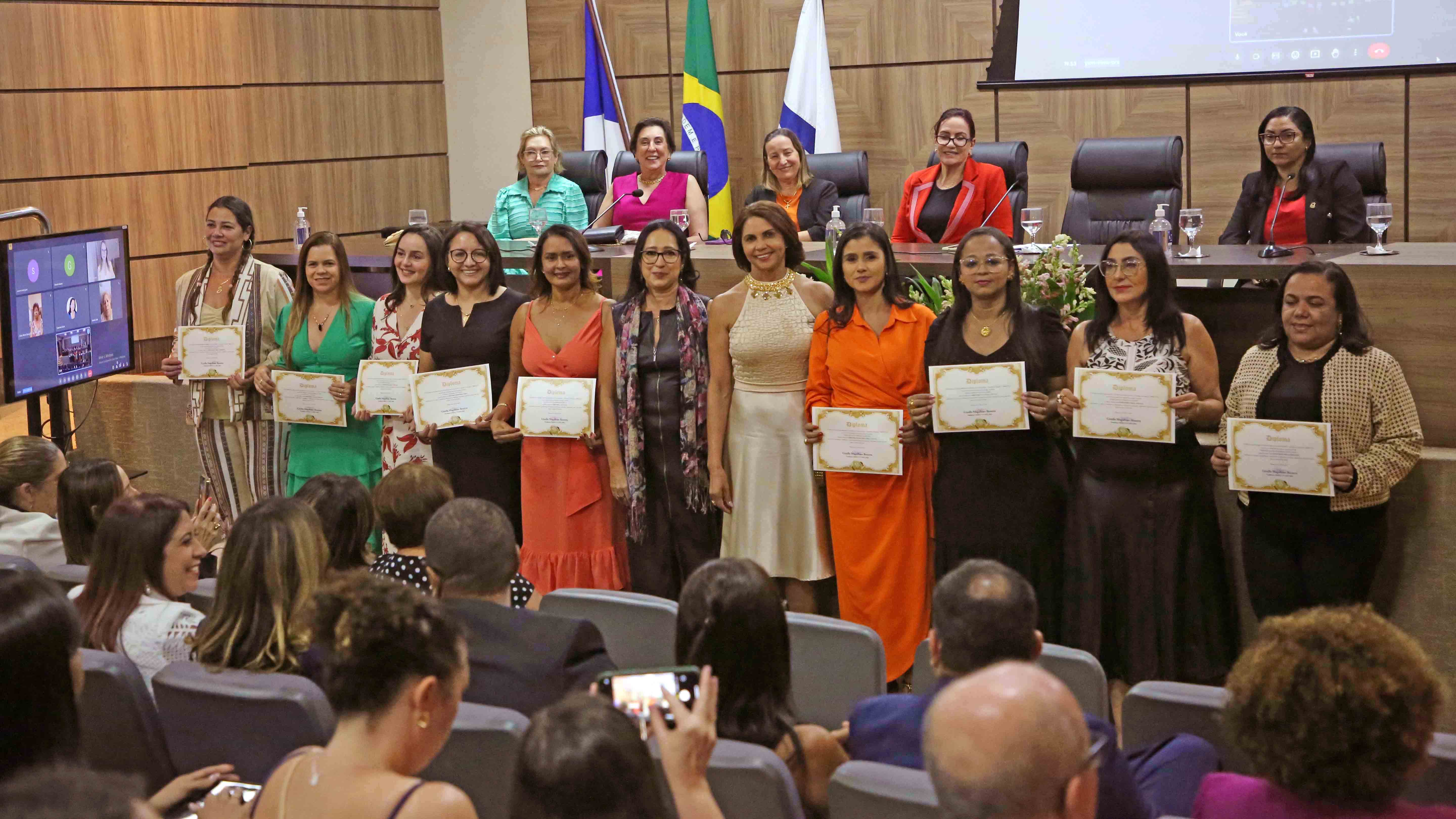 Imagem mostra uma mesa com várias autoridades mulheres durante cerimônia  de posse 