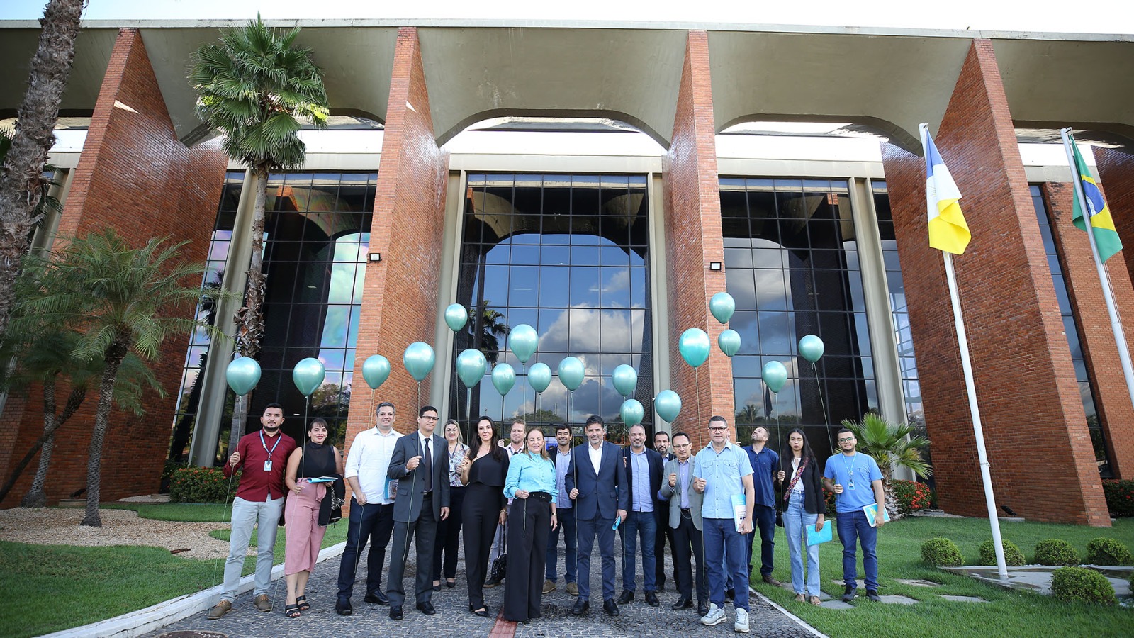 Homens e mulheres com balões verdes em frente à sede do TJTO