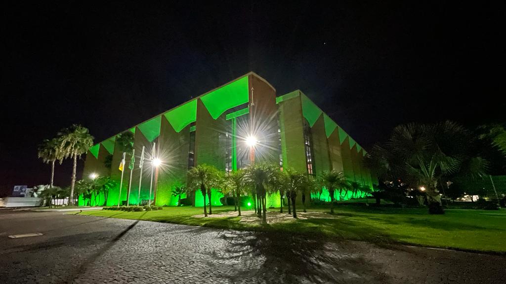 Imagem mostra a fachada do prédio do TJTo iluminado com a cor verde em homemagem à Defensoria Pública