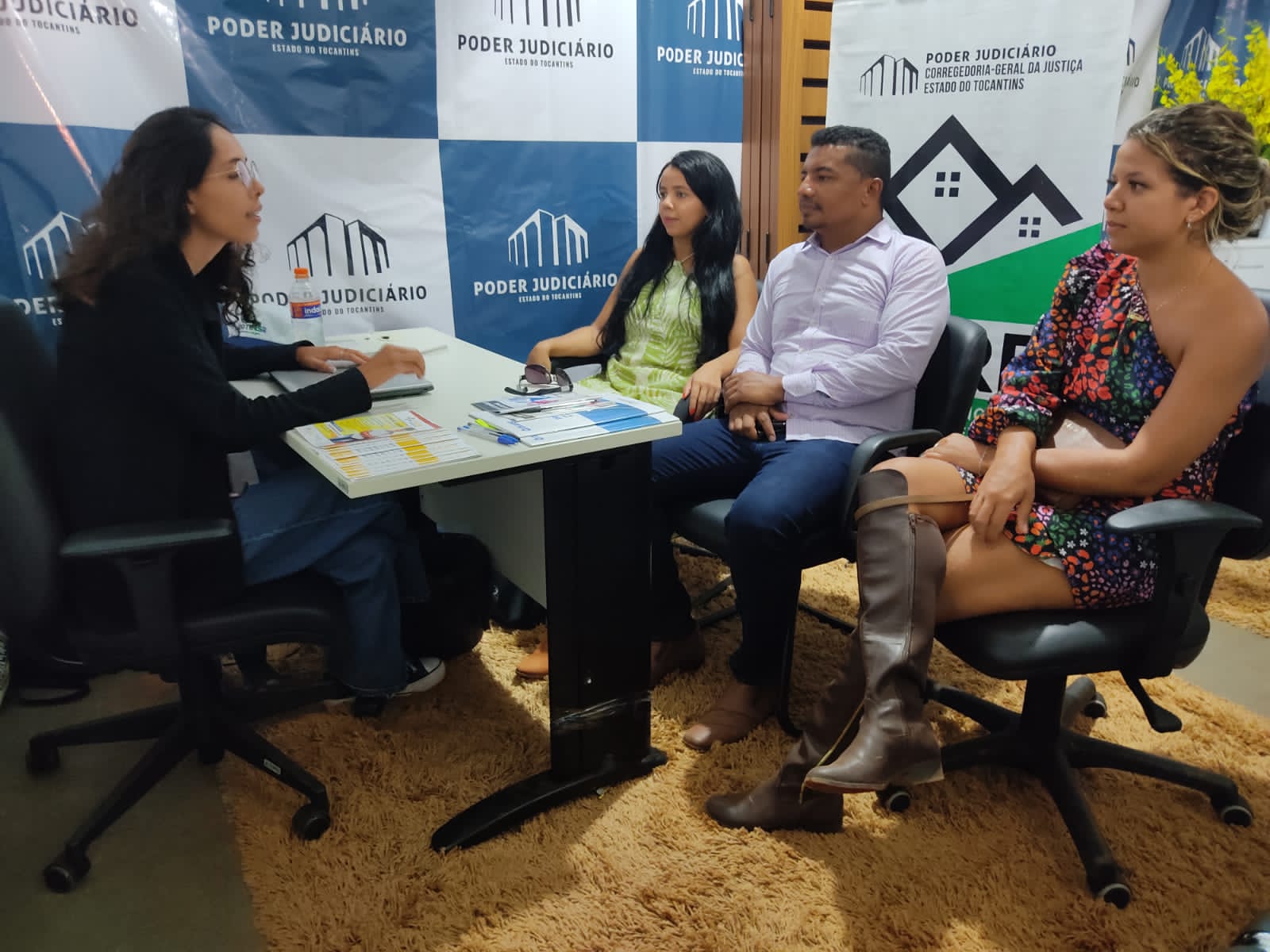 pessoas sentadas sendo atendidas por servidora do judiciário