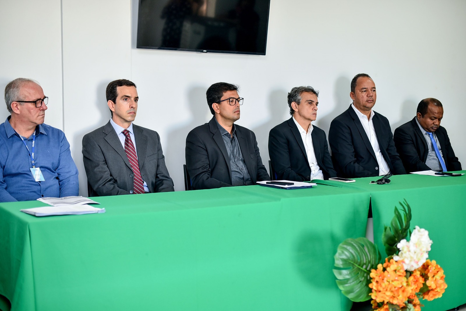 representantes de instituições sentados ao longo de uma grande mesa