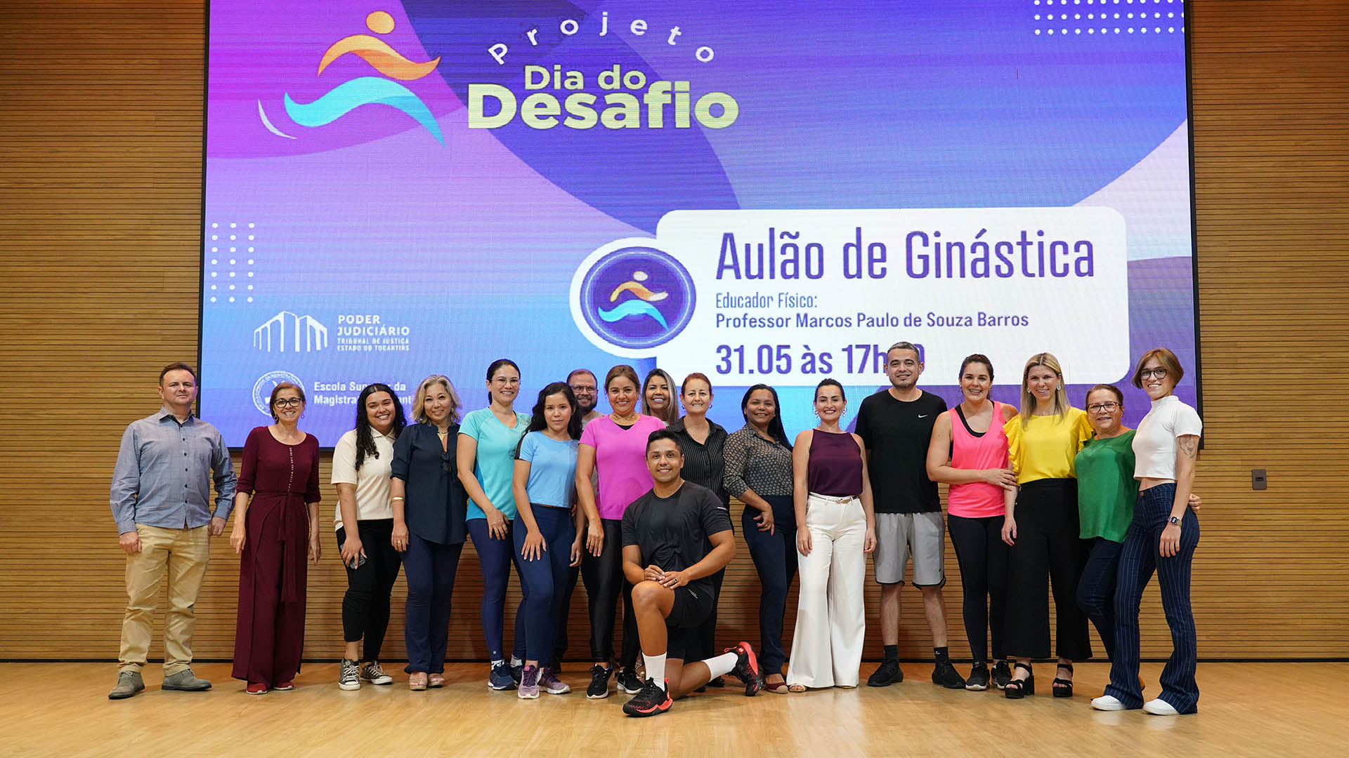 Imagem mostra várias pessoas em é e atrás um banner sobre o Dia do Desafio