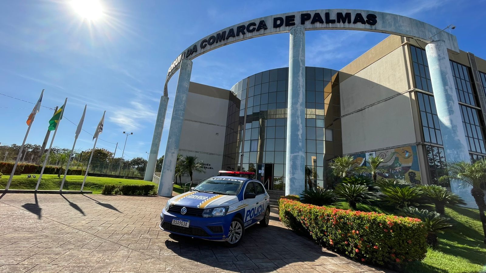 Imagem colorida da fachada do prédio do Fórum de Palmas. Há um carro da Polícia militar na frente