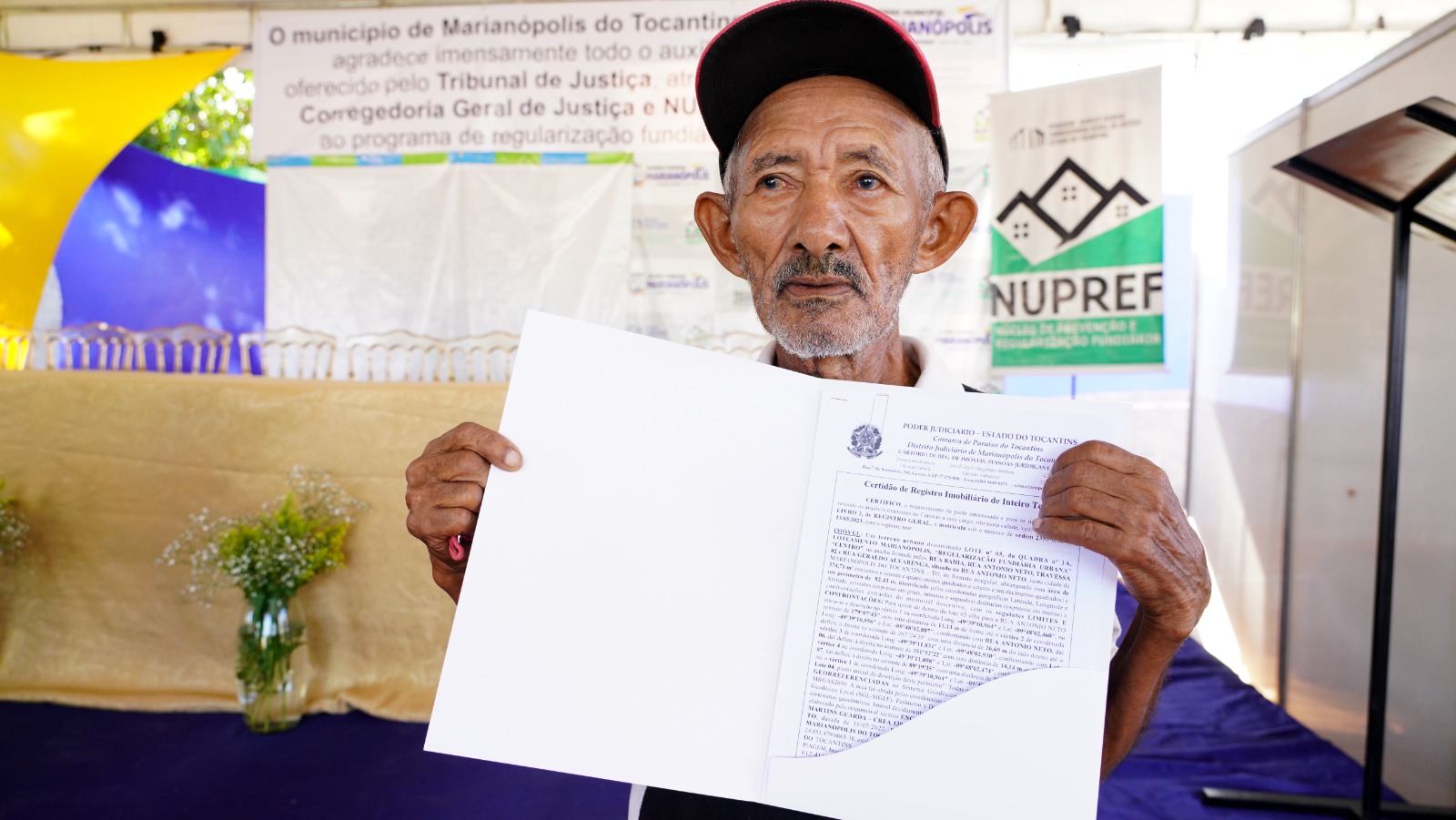 Seu Firmino posando para foto segurando o título de sua propriedade