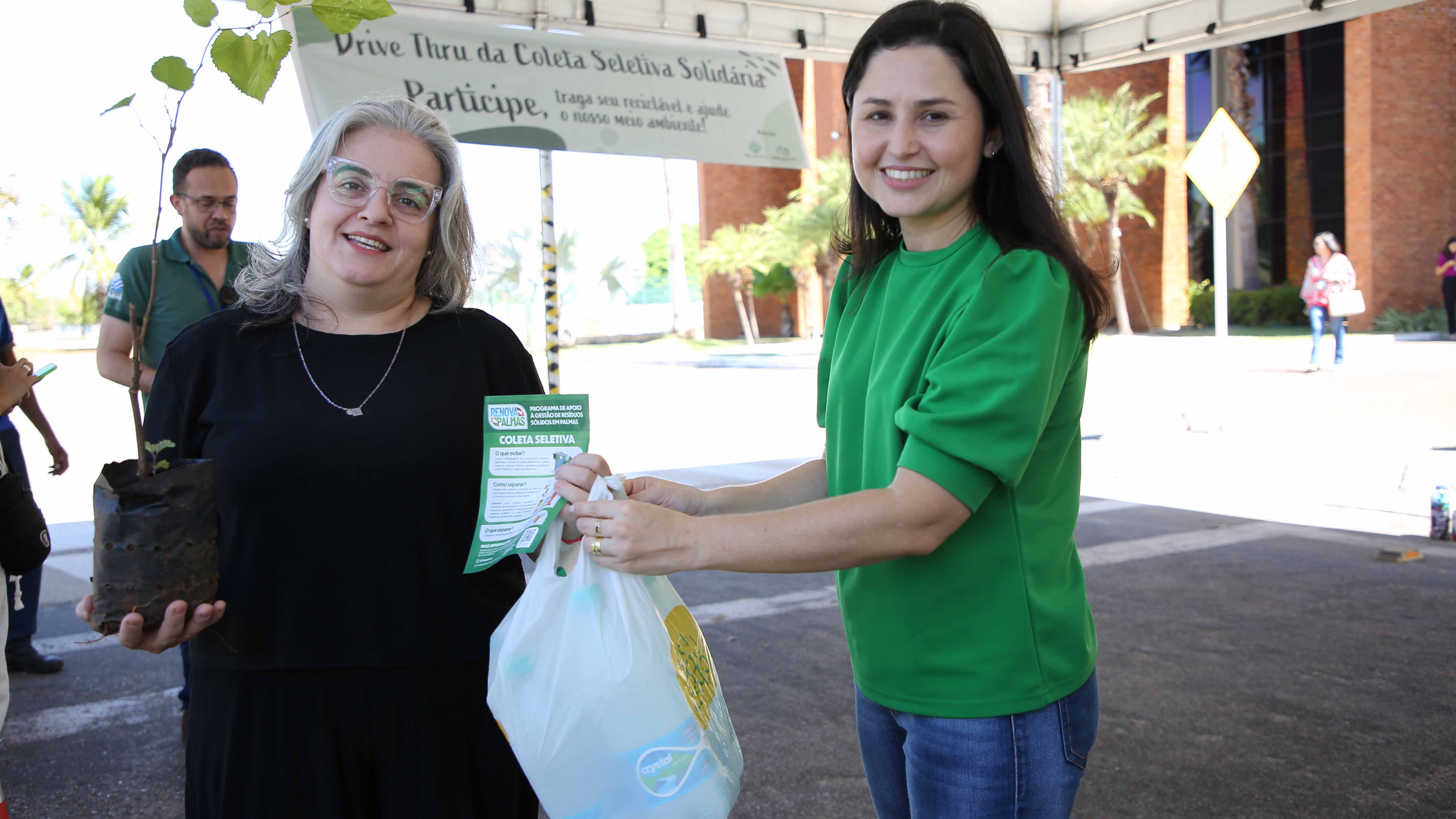Mulher grisalha segura muda de planta com mulher morena clara