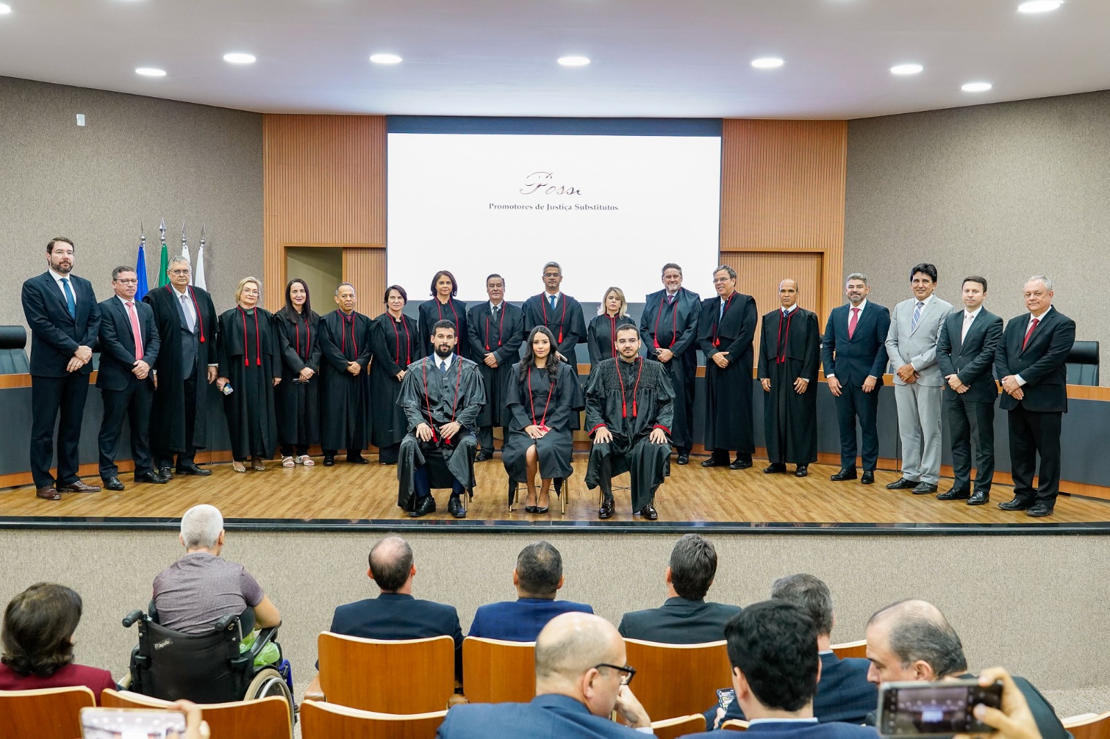 Imagem colorida que mostra homens e mulheres de toga em um ambiente fechado