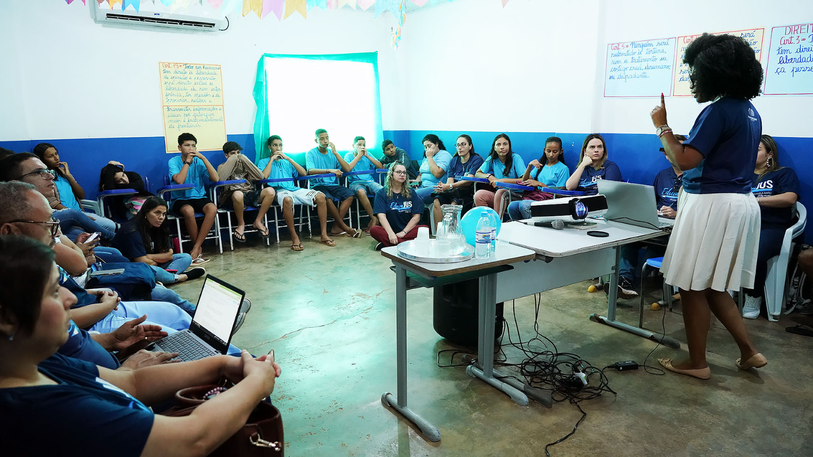 Mulher negra conversa com alunos em sala de aula