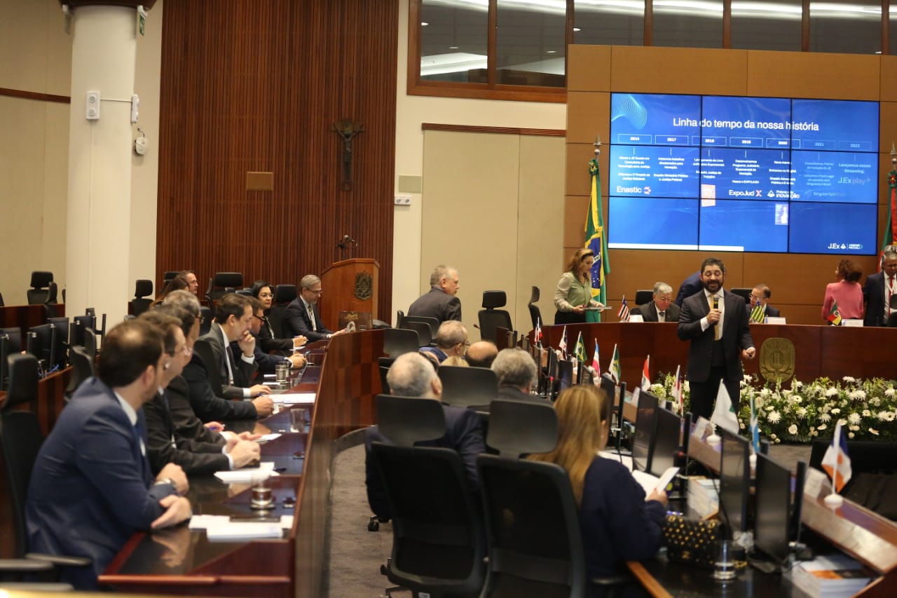 Imagem colorida de autoridades sentados à mesa observando uma palestra