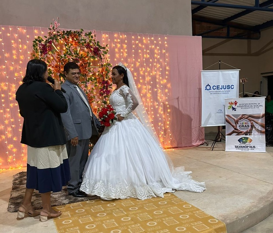 Casal de noivos em pé durante celebração realizada por juíza 
