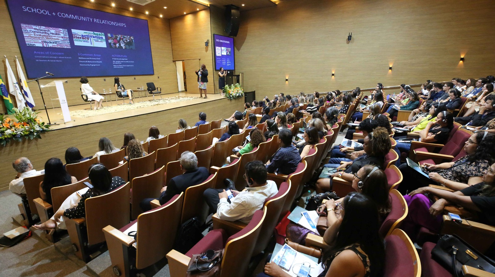 Foto de pessoas sentadas no auditório durante palestra de professora americana, uma mulher negra de cabelos compridos trançados