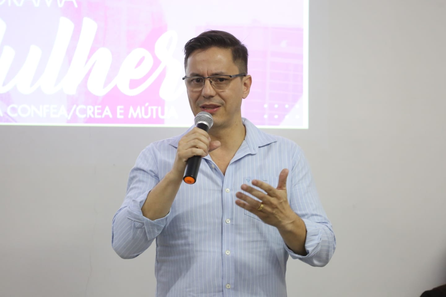 Homem branco de óculos fala ao microfone