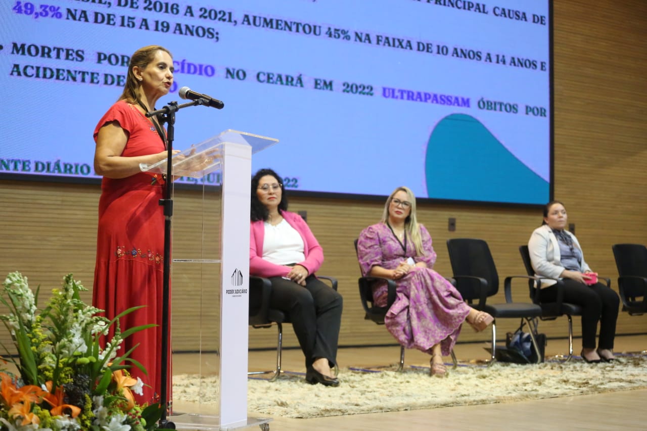 Raimunda, de vestido vermelho, com três mulheres sentadas à direita, durante evento no TJTO