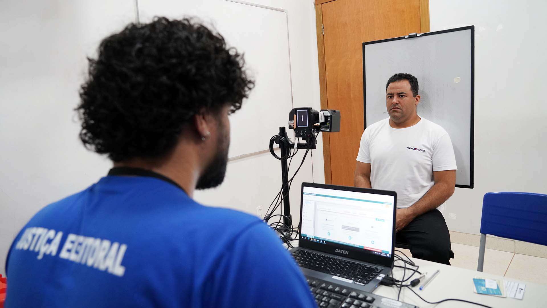 Homem de camisa branca é fotografado por outro de camisa azul