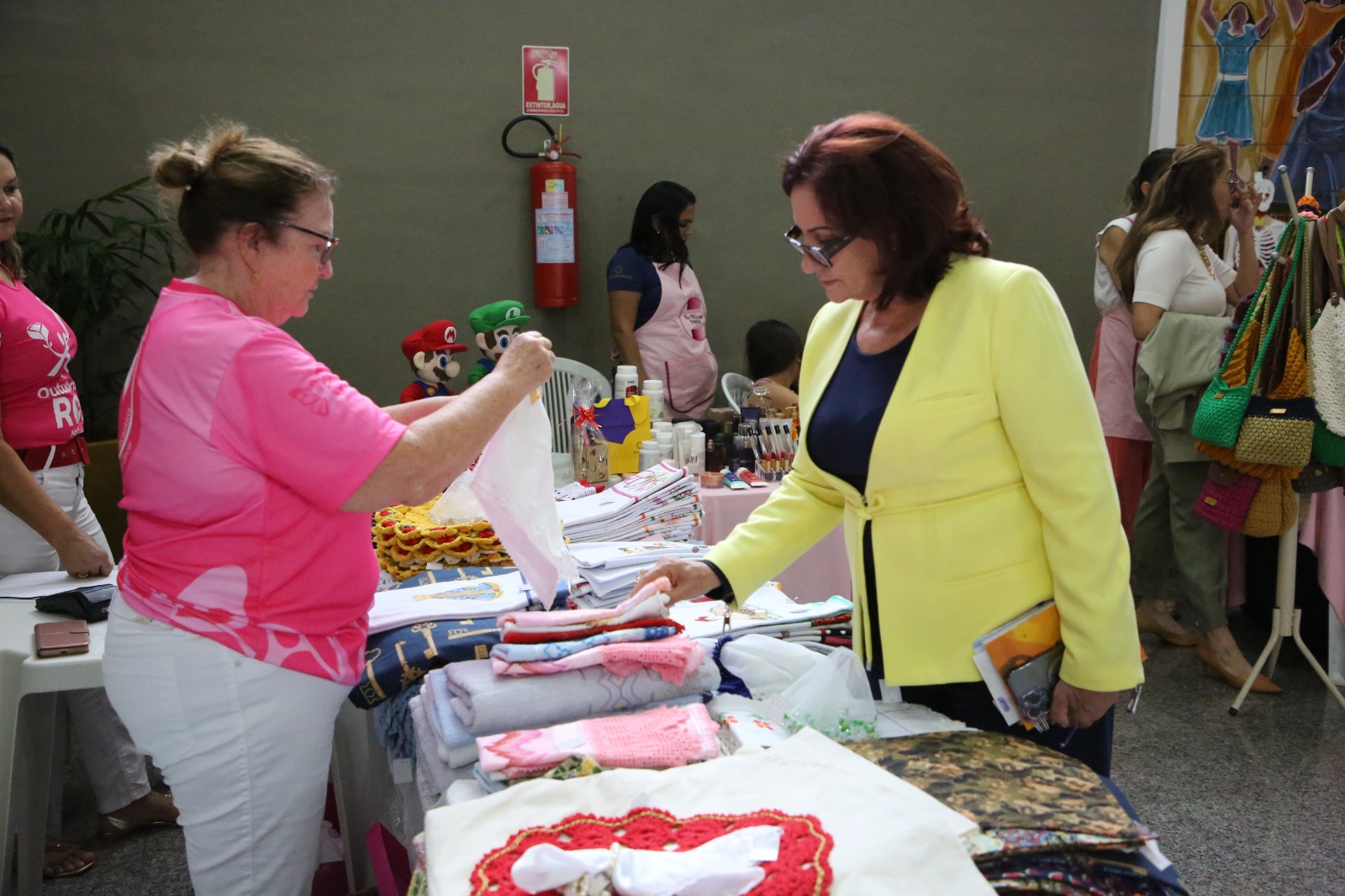 Mulher  com produto na mão conversando com expositora