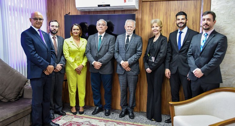 Fotografia colorida que mostra seis homens e duas mulheres bem vestidos, posando para a foto na posse do desembargador Adolfo Amaro no TRE