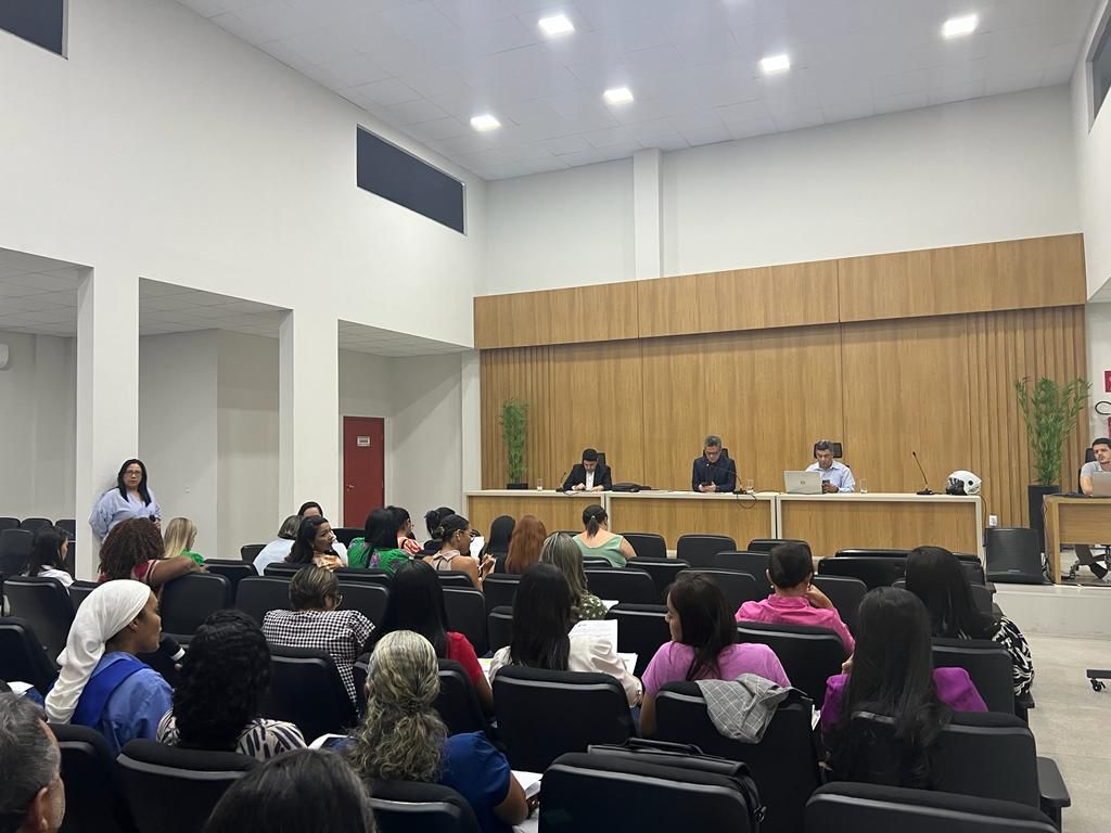 Imagem mostra uma mesa no alto com pessoas atrás e à frente várias pessoas sentadas