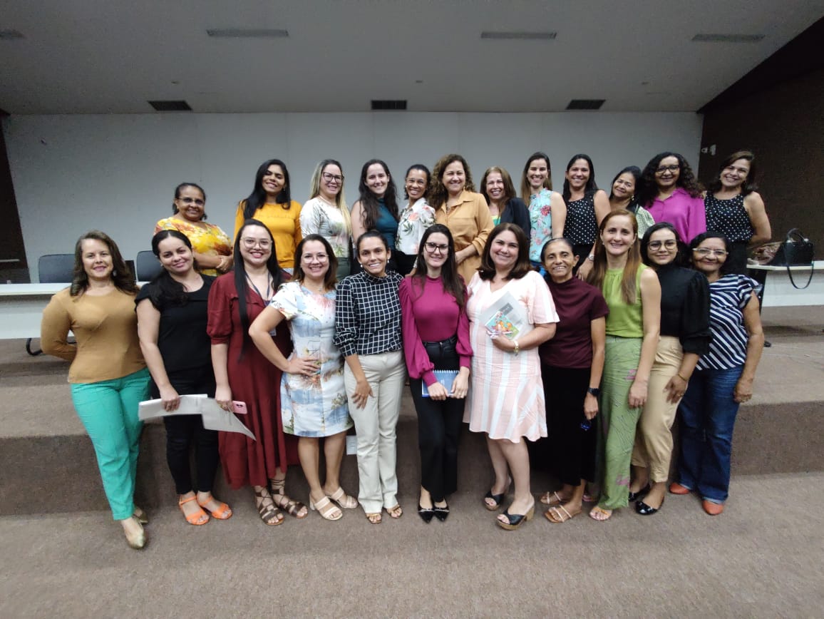 Fotografia colorida de um grupo de mulheres em pé posando sorrindo  