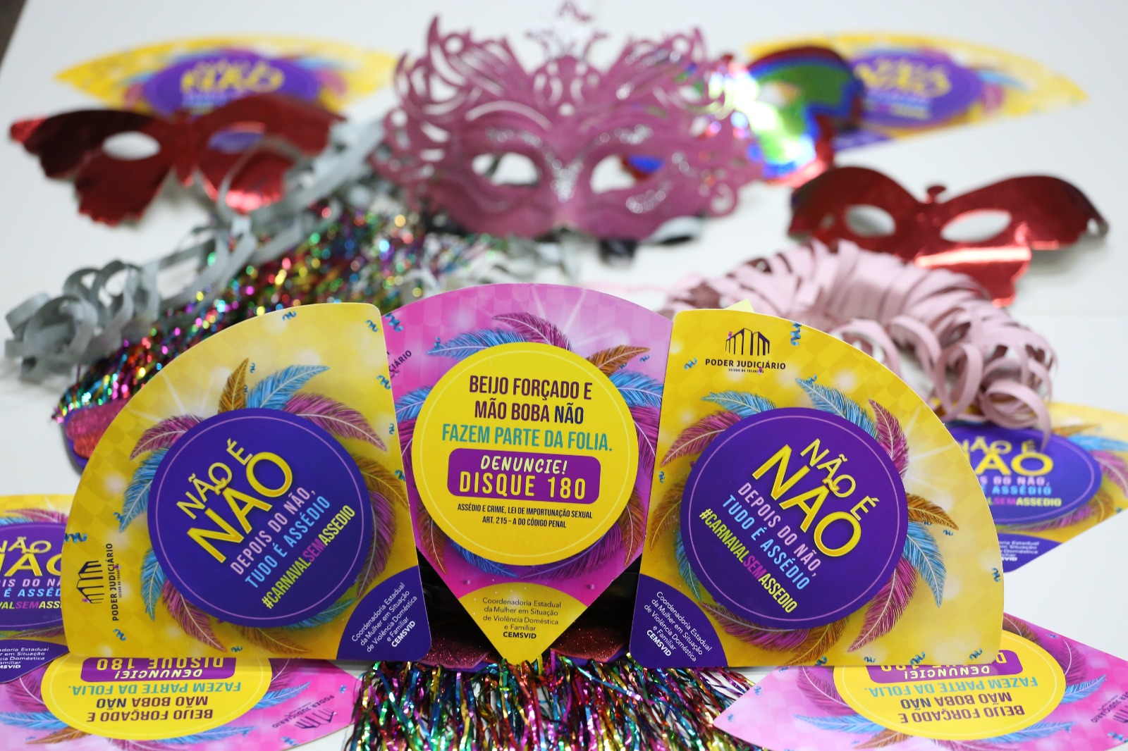 Imagem com as cores rosa, roxo, amarelo e com acessórios de Carnaval mostra o panfleto da campanha Assédio não é Paquera