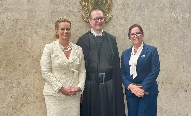 desembarga Etelvina à esquerda, de blazer e calça azul e bluza branca; o ministro empossado ao centro de beca escura, e sua esposa de terninho claro à direita