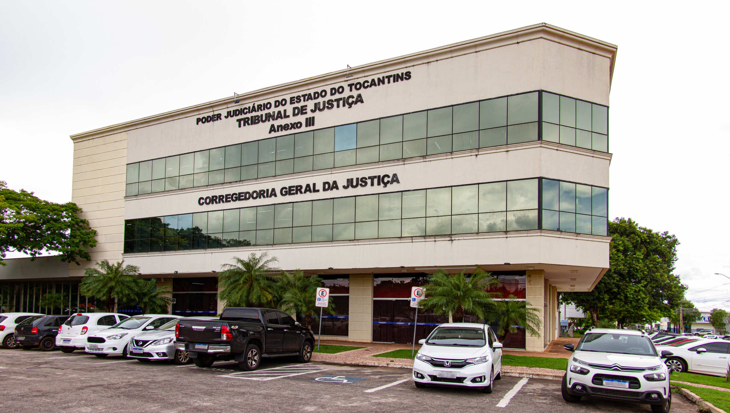 Fotografia colorida da corregedoria geral de justiça com carros na frente 
