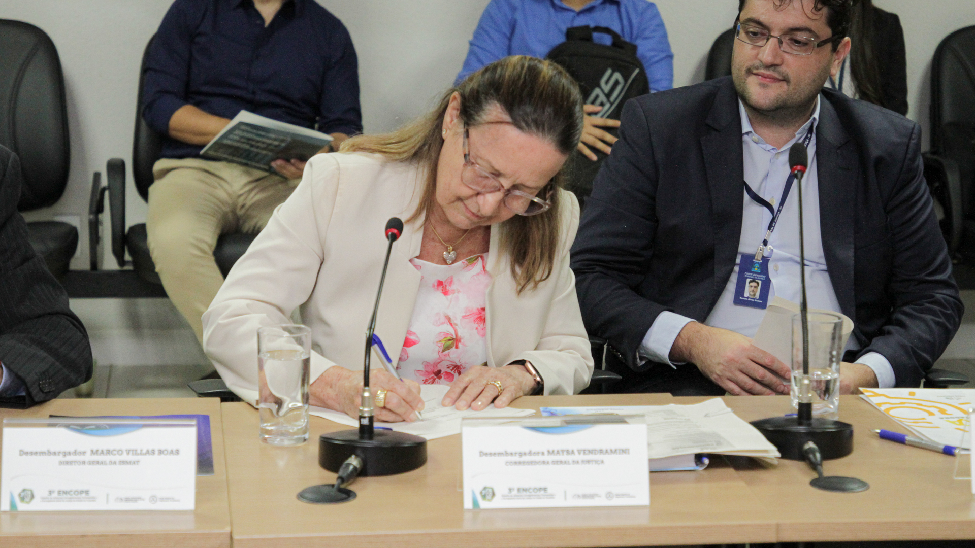 Fotografia colorida de desembargadora Maysa Vendramini Rosal assinando a carta de encerramento do evento