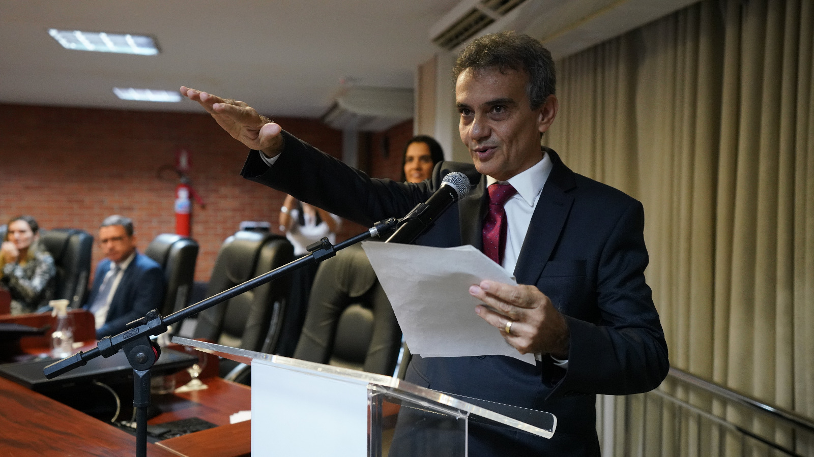 homem com braço direito estendido fala ao microfone