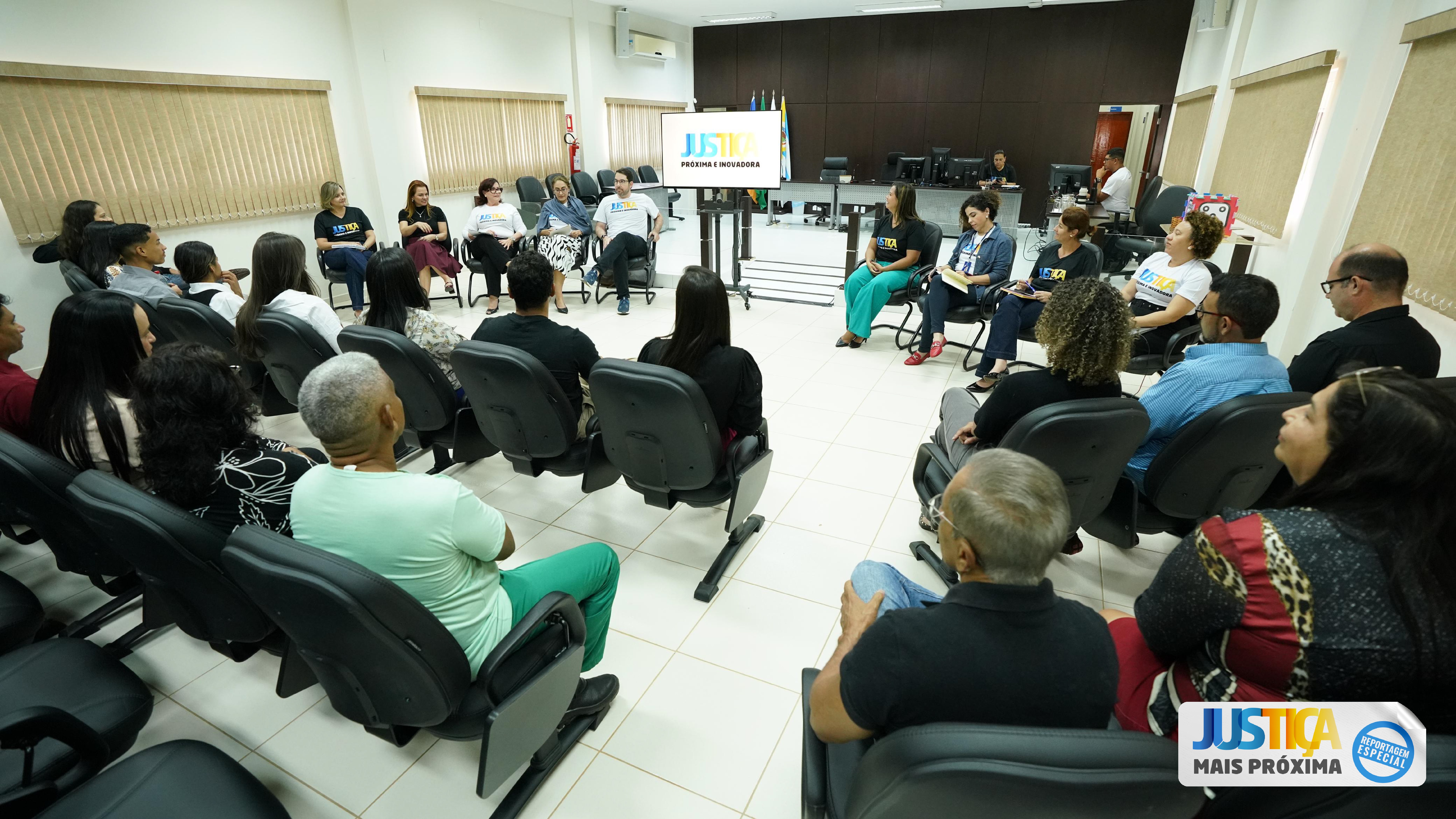 Fotografia colorida que mostra um salão cheio de pessoas prestando atenção em uma apresentação à frente