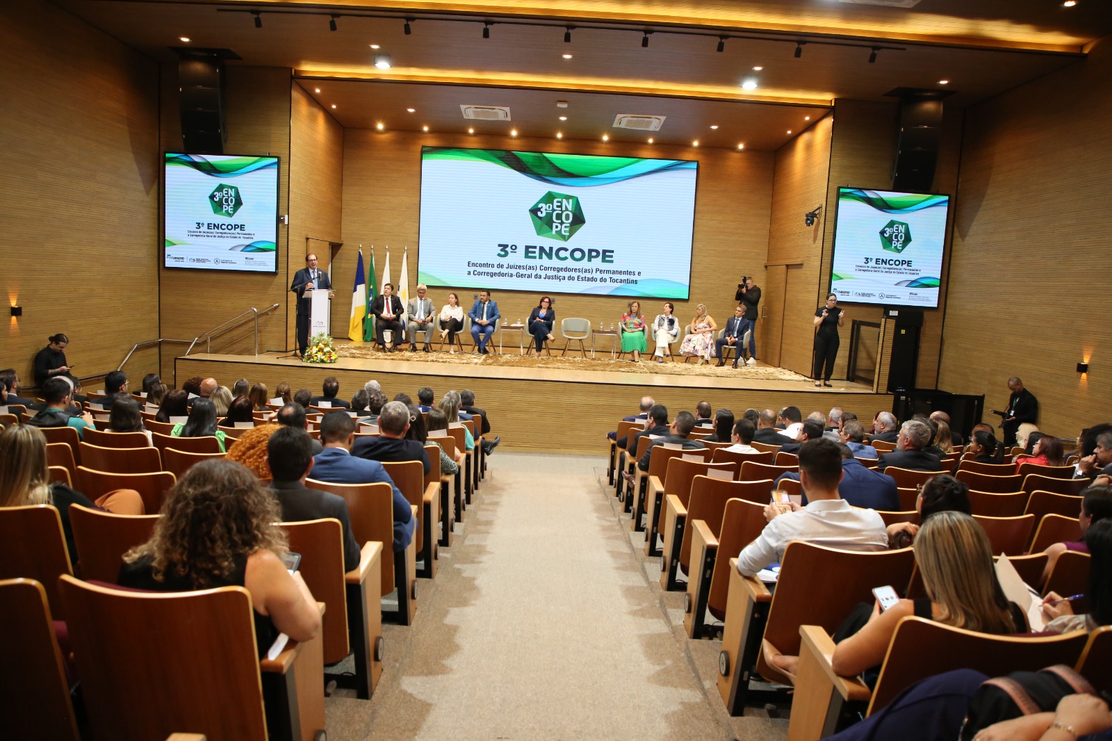 Fotografia colorida onde convidados estão sentados nas cadeiras do auditório do Tribunal de Justiça do Tocantins, enquanto o ministro Luís Felipe Salomão discursa em um microfone posto em cima de um palanque 