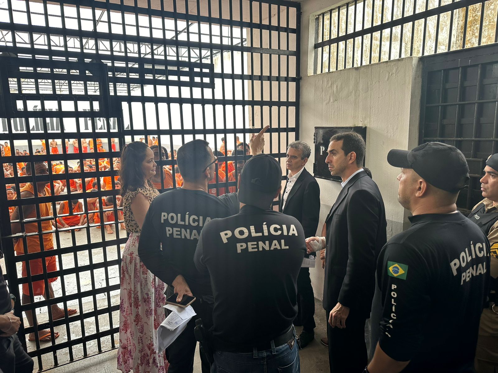 Imagem do juiz Allan Martins, autoridades e policiais penais uniformizados em visita à Casa de Prisão Provisória de Palmas; ao fundo grades 