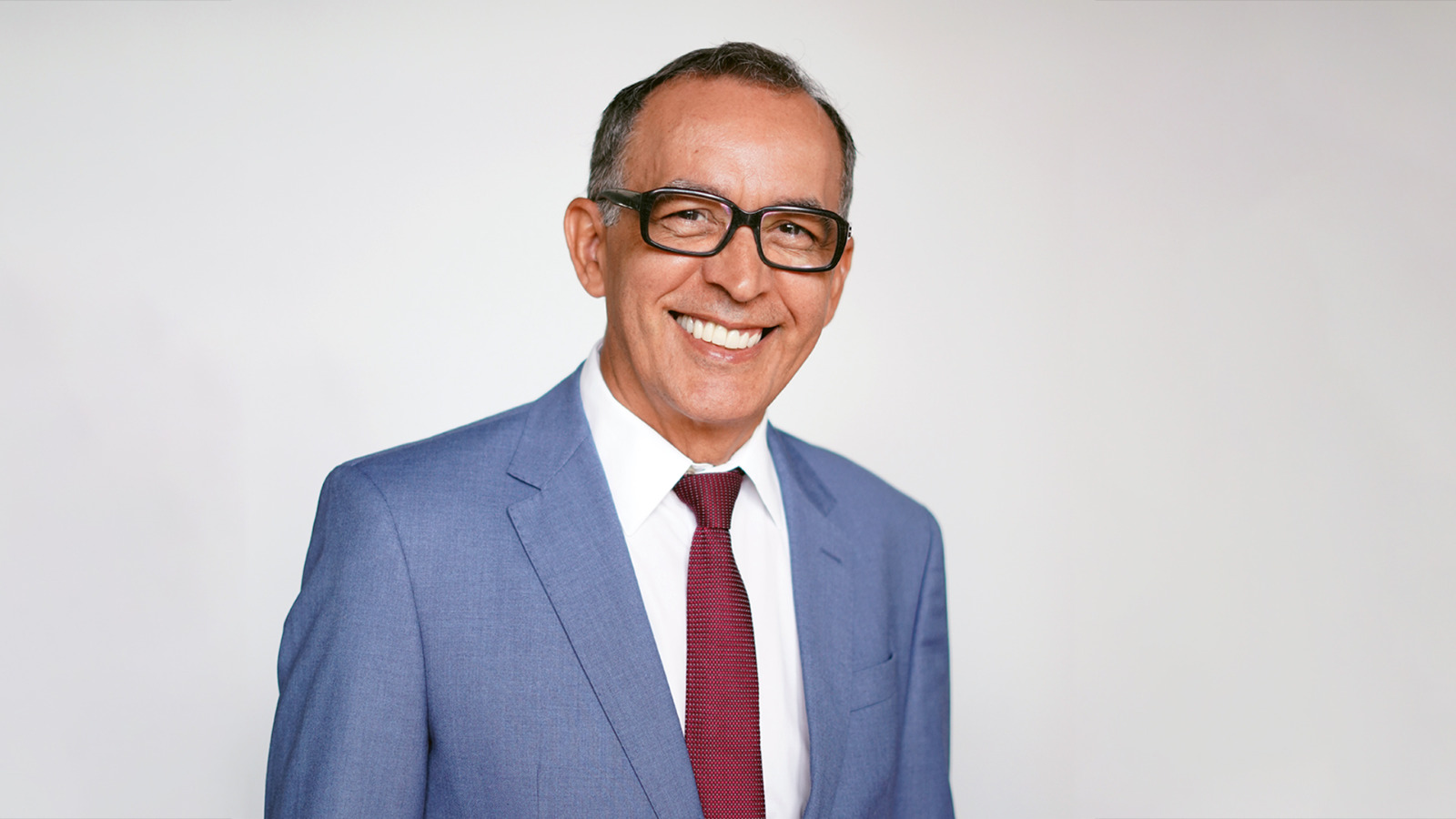 juiza Gil correa, usa óculos, camisa branca, blazer azul claro e gratava vermelha