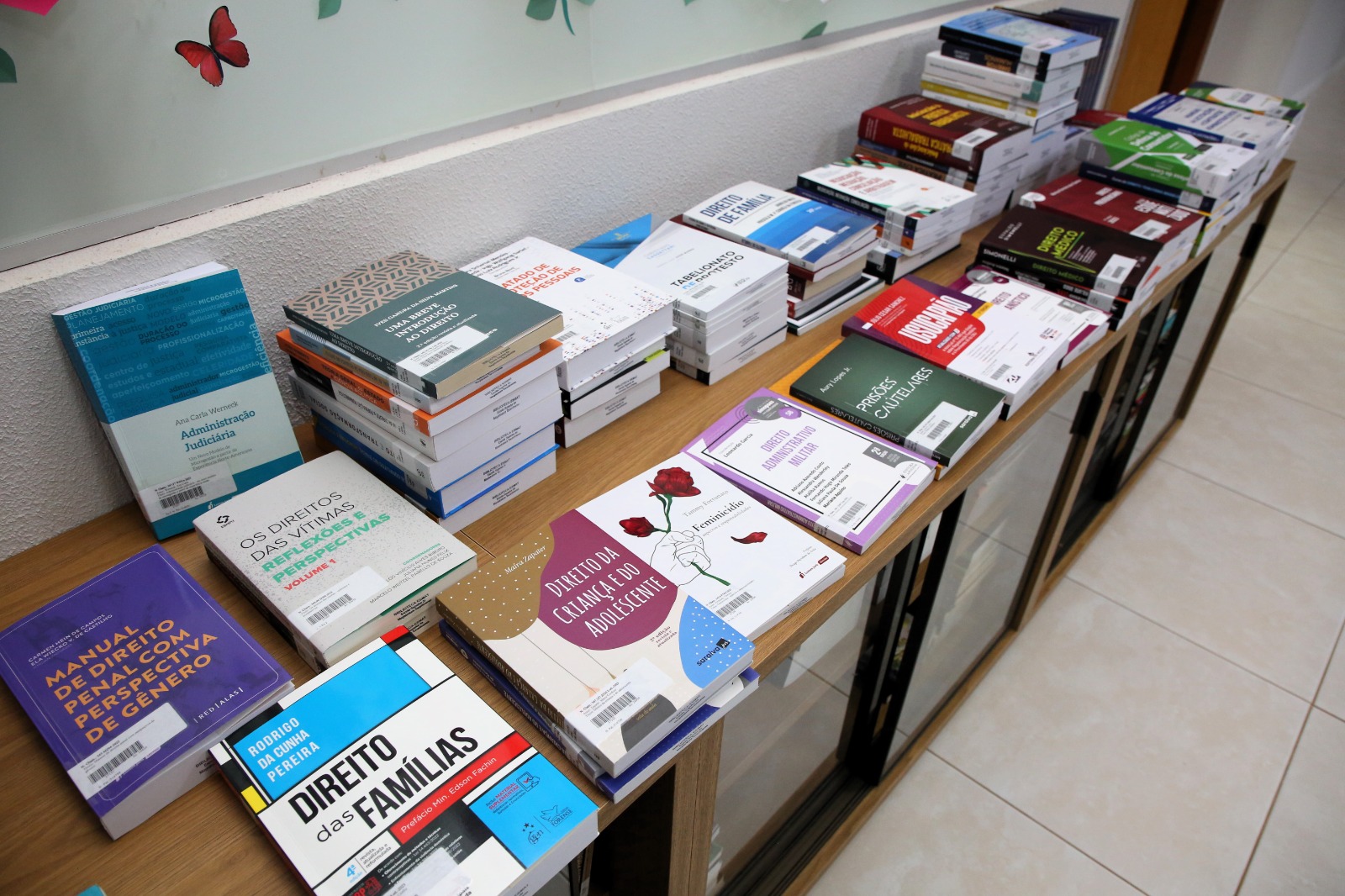 Fotografia colorida de uma mesa de madeira cheias de livros do poder judiciário adquiridos pela Esmat