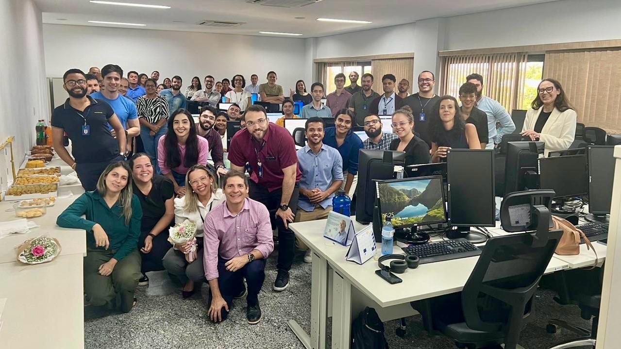 pessoas reunidas em uma sala celebram o primeiro mes de atuação da cpe