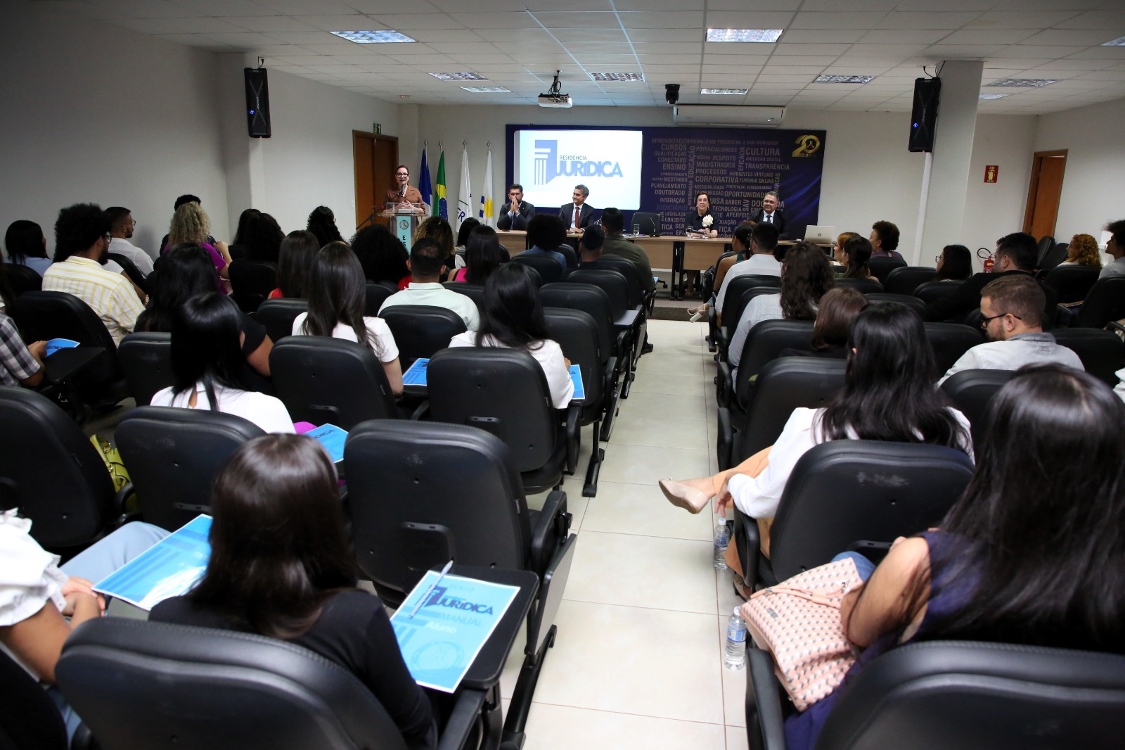 pessoas sentadas em um auditório assistem ao pronunciamento da presidente do TJTO