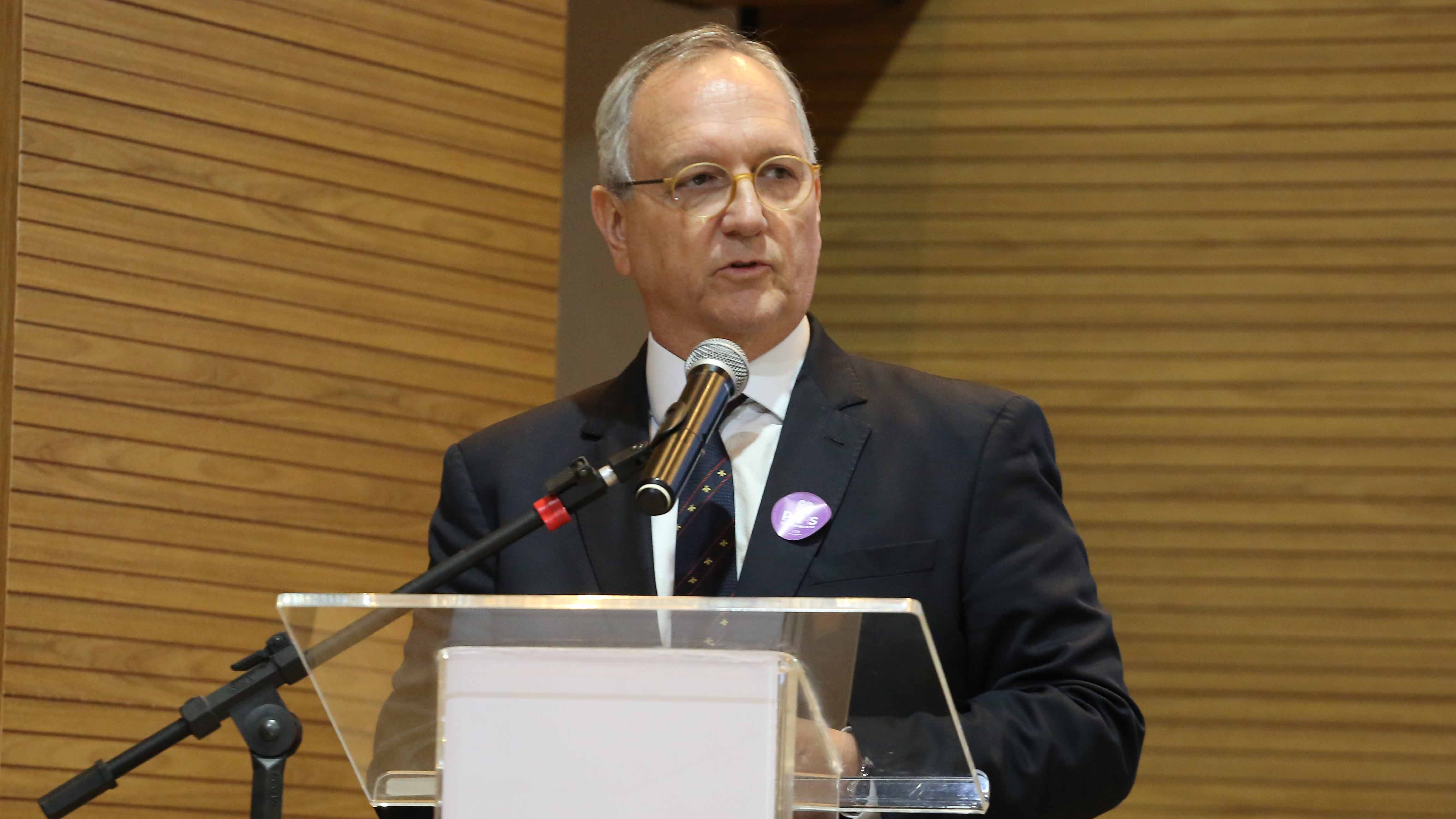 desembargador Pedro Nelson, um homem branco de cabelos grisalhos, usa óculos, camisa branca e terno escuro