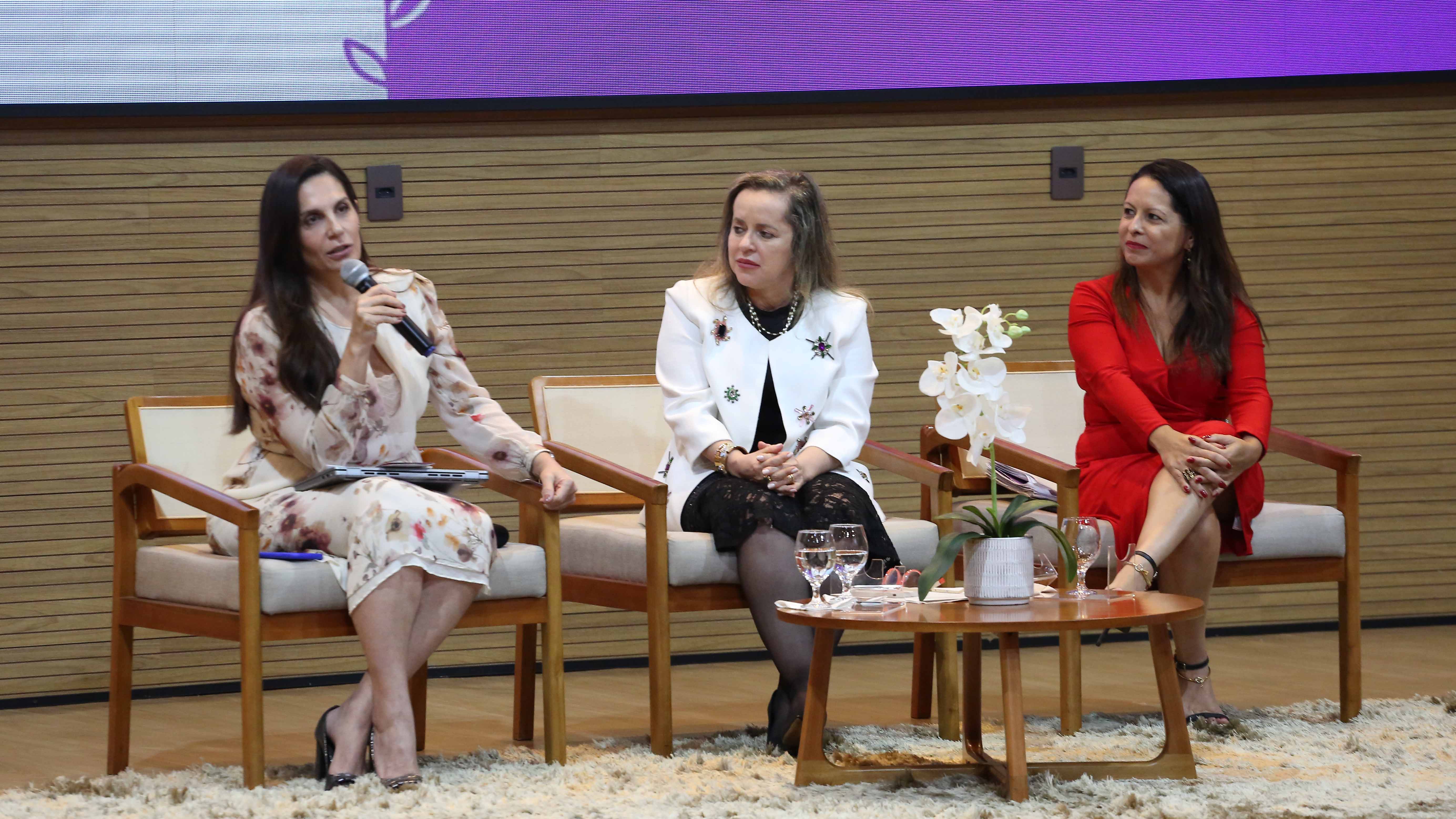 três juízas sentadas no palco do auditório do TJTO