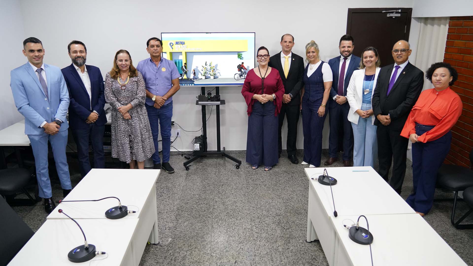 Homens e mulheres em pé ao lado de uma TV que projeta a imagem do PID Almas