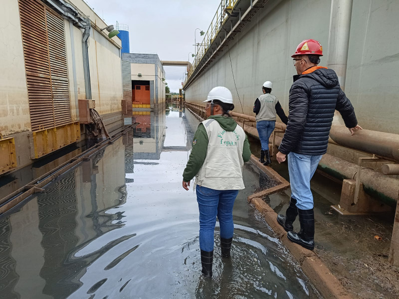 Fotografia colorida que mostra dois homens e uma mulher em meio às águas da enchente no Rio Grande do Sul