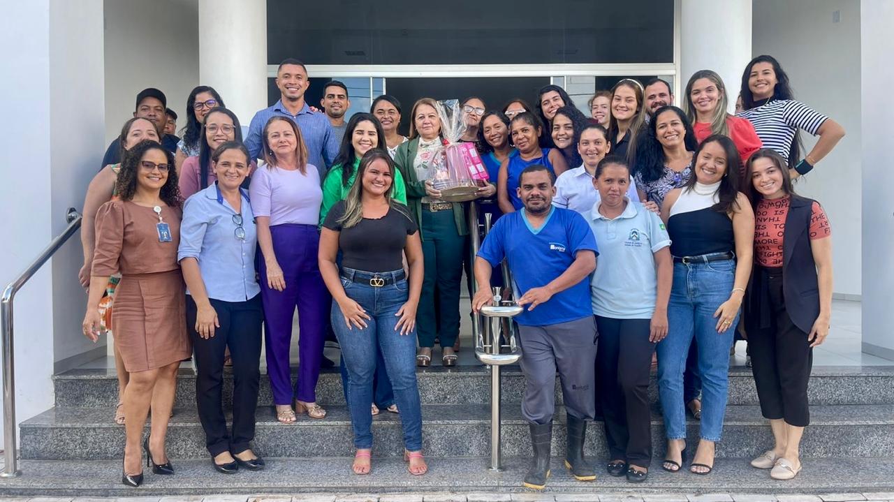 homens e mulheres estão em uma escada posicionados para foto ao lado da juíza nely alves que segura uma cesta de café da manhã