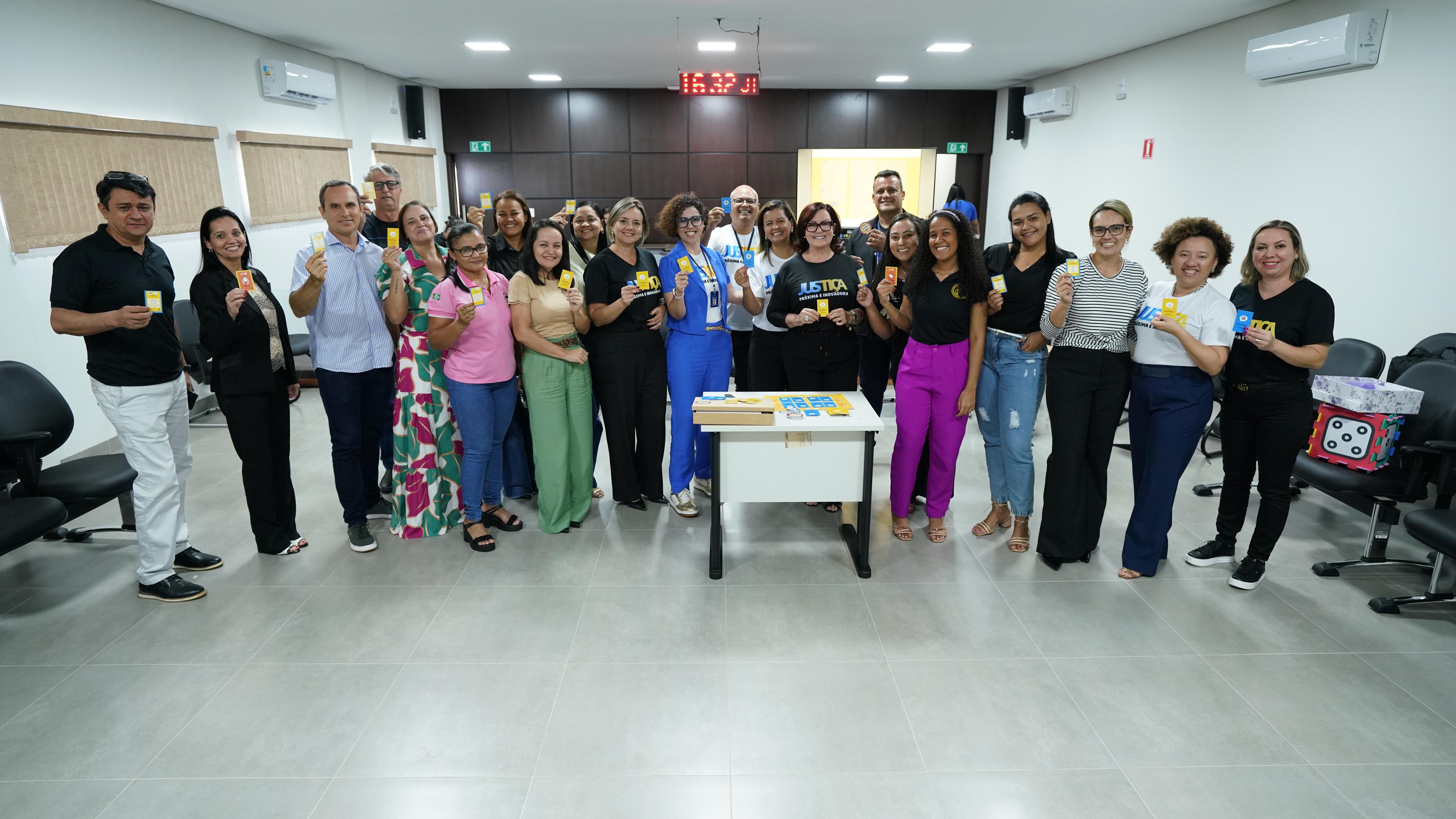 Fotografia colorida que mostra homens e mulheres posando para a imagem, em pé, em uma sala. 