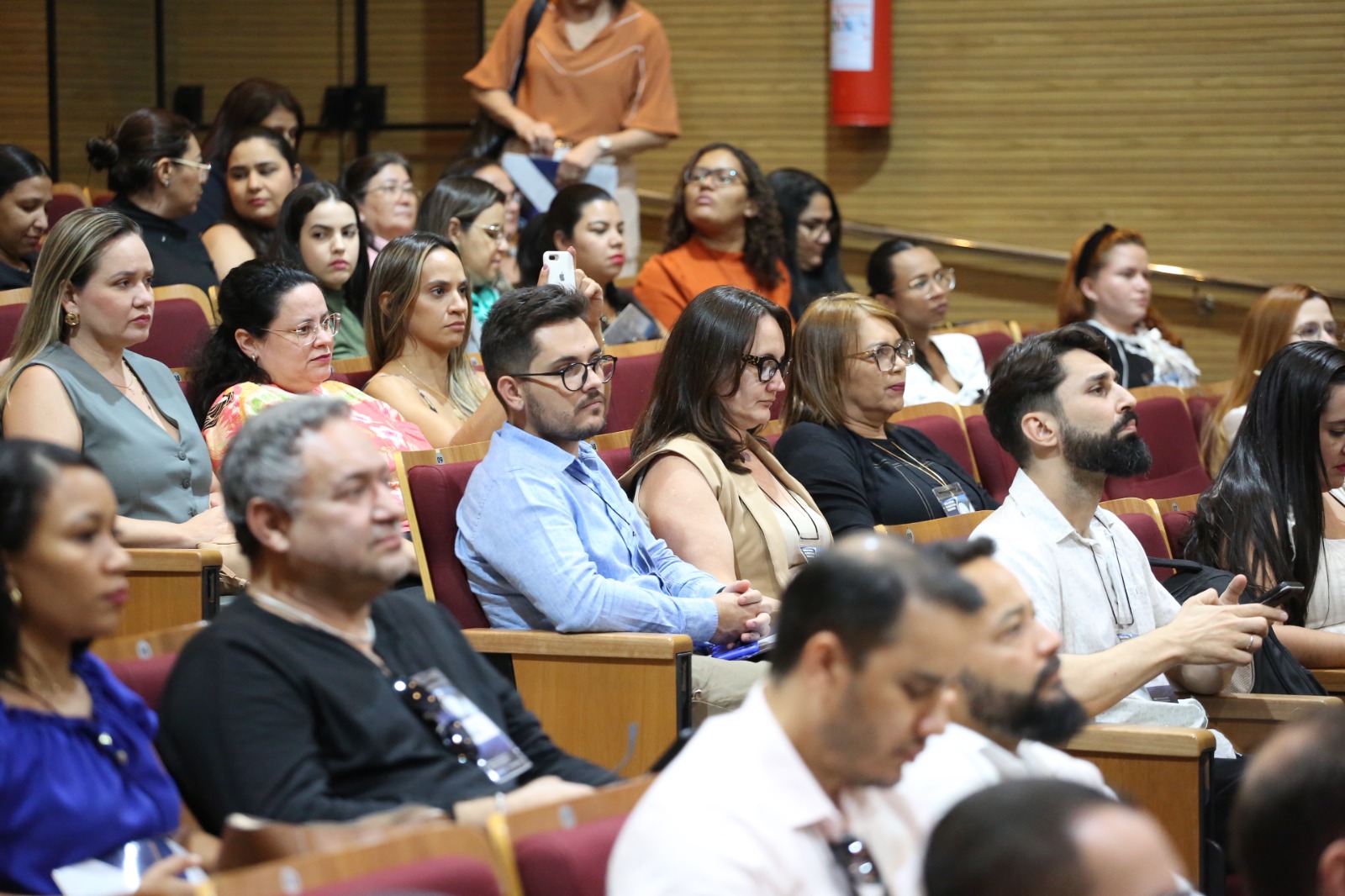 Fotografia colorida que mostra pessoas prestando atenção à palestra
