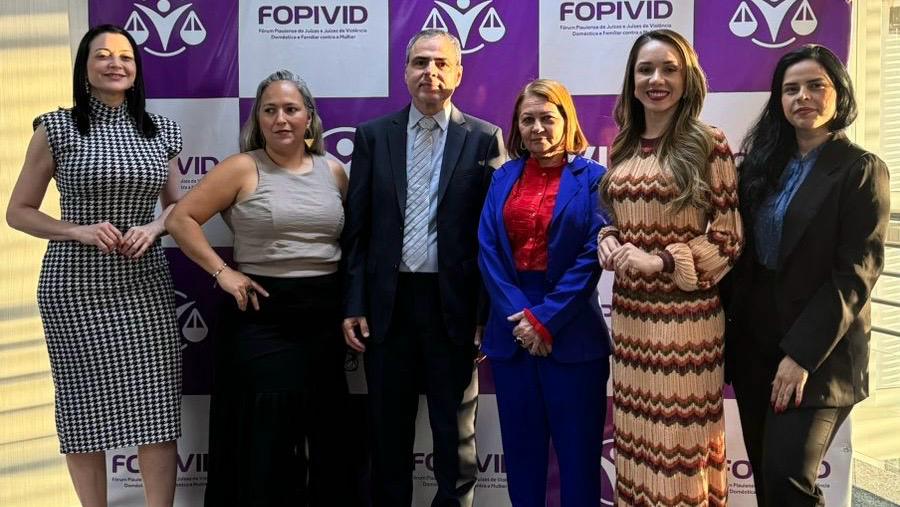 Foto com 6 pessoas em pé, sendo um homem todos posando para a foto