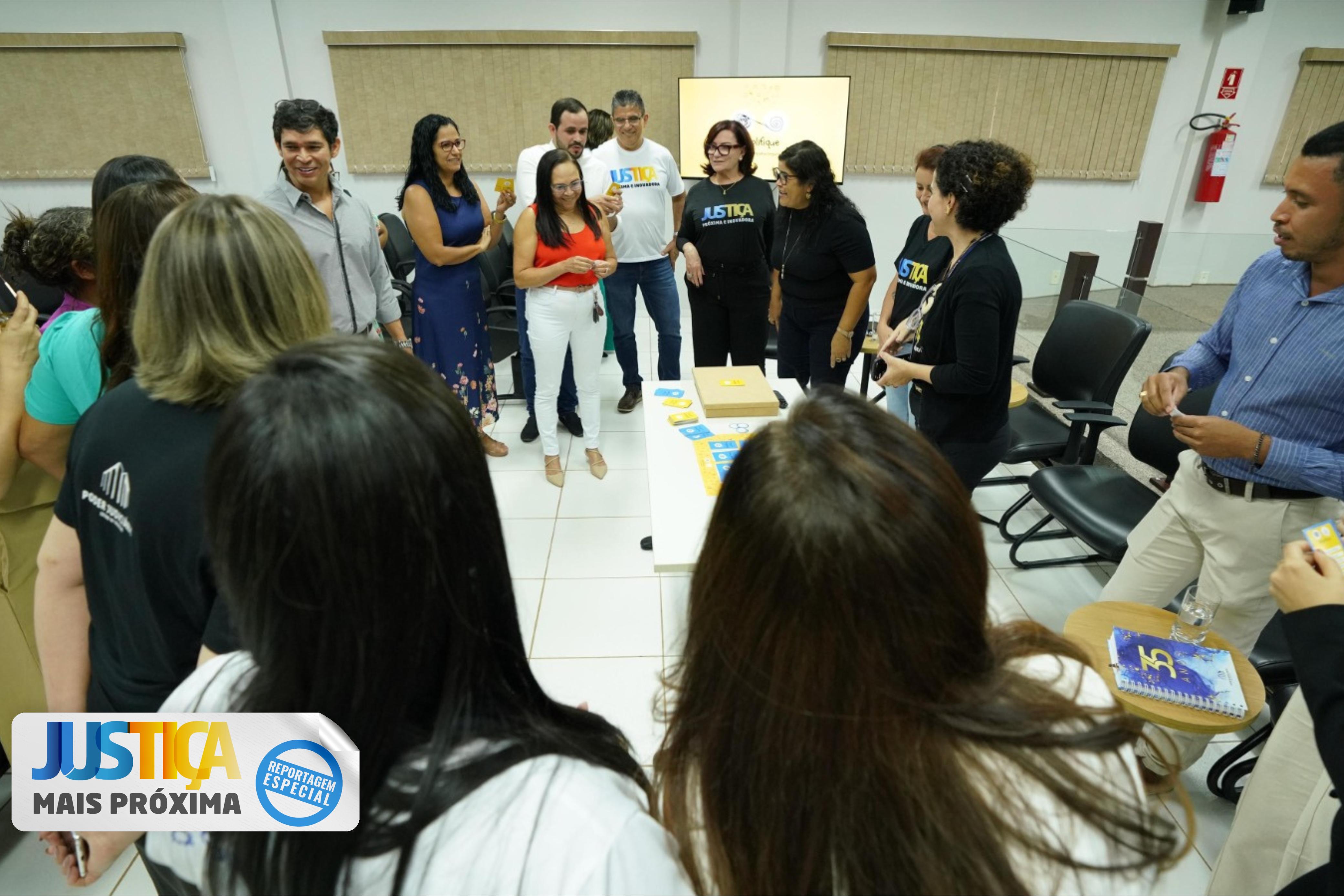 Homens e mulheres em pé formam toda de diálogo em sala de paredes brancas com persianas beges