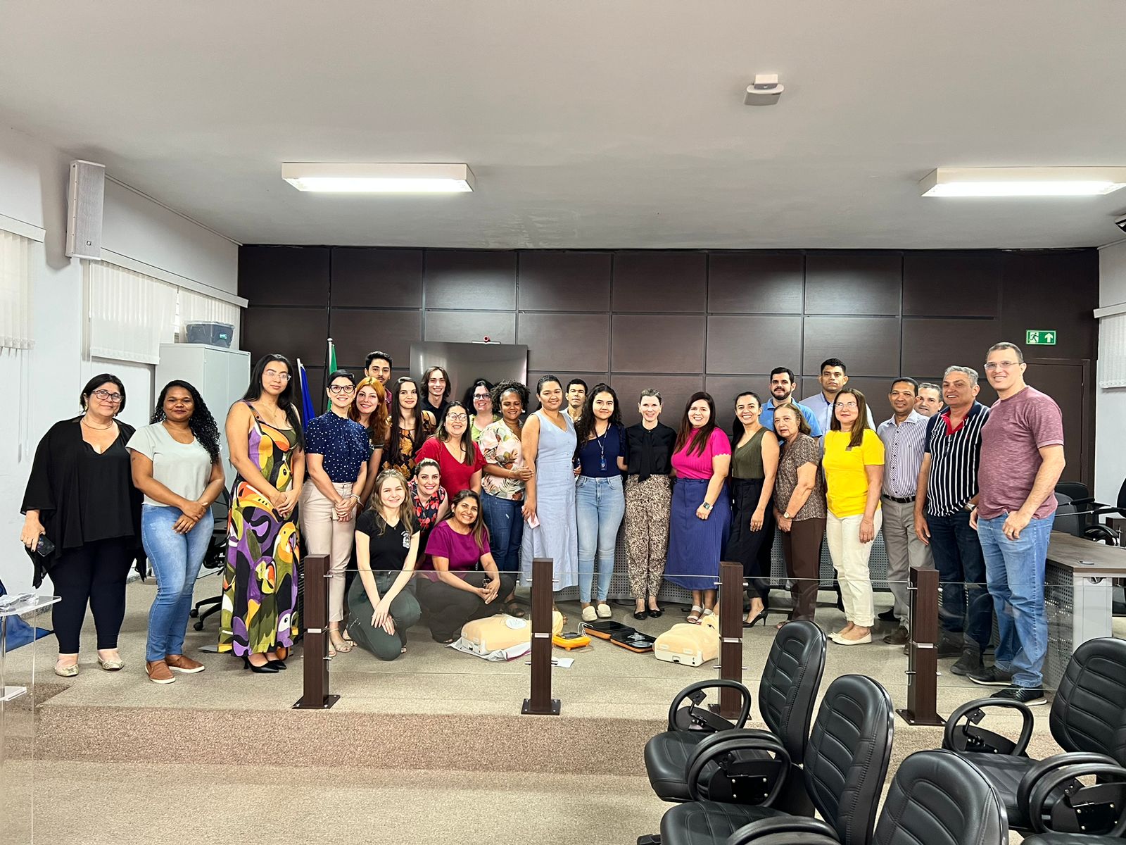 Fotografia colorida que mostra pessoas  em pé, numa sala de audiências, posando pra foto.